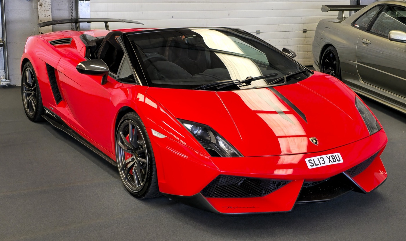 Red Lamborghini Gallardo LP570-4 Spyder Performante with a black centre stripe and fixed rear wing, indoors