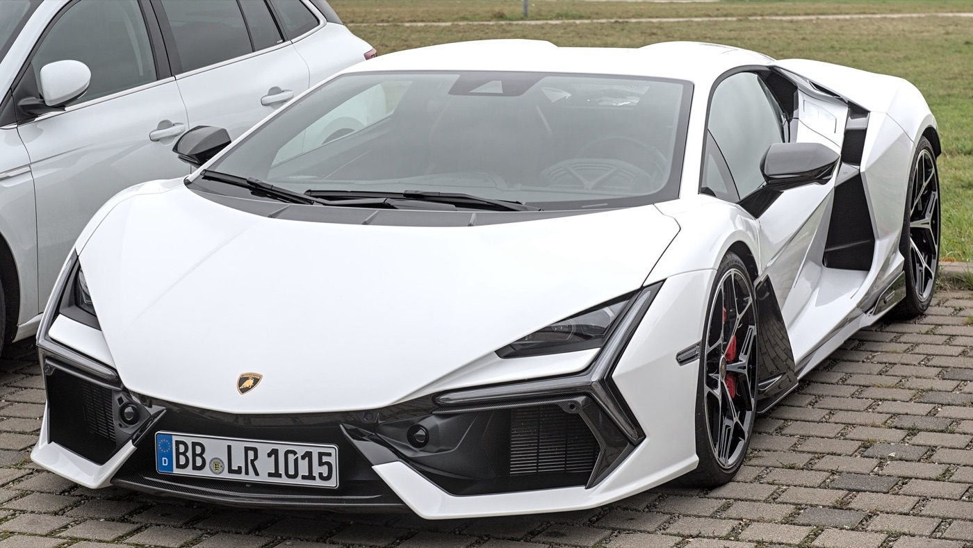 White Lamborghini Revuelto hybrid supercar with black Y-shaped headlight surrounds parked on a block-paved car park