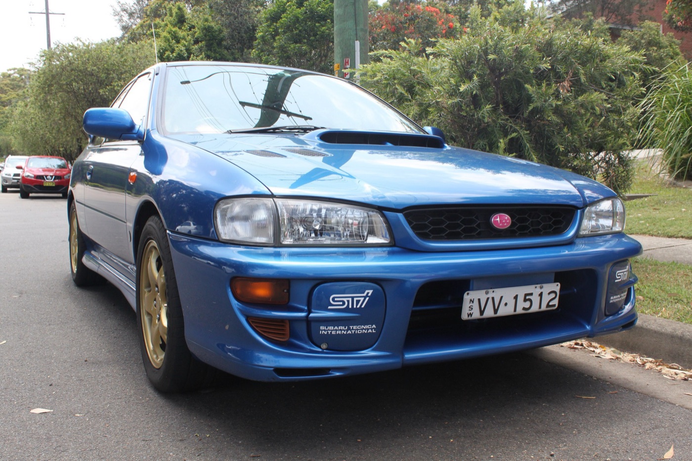 Blue 1999 Subaru Impreza WRX STi Version 5 coupe with gold wheels parked at a kerb