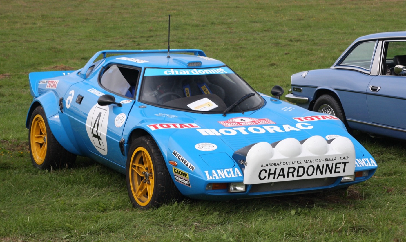 Blue Lancia Stratos rally car in Team Chardonnet colours with yellow wheels and a pod of four spotlamps on the bonnet