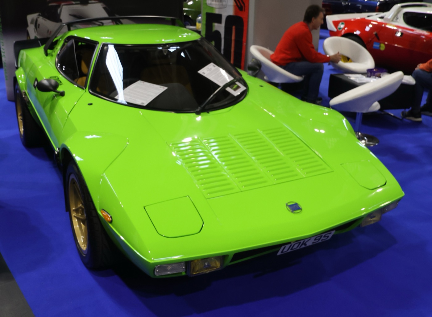 Lime green Lancia Stratos replica with gold wheels and a British number plate on a show stand