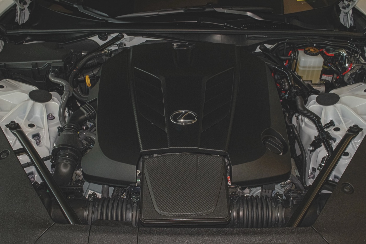 The black engine cover of the Lexus 2UR-GSE V8 with the Lexus badge, seen from above in the engine bay of an LC 500