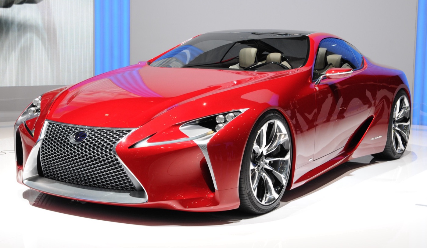 Red Lexus LF-LC concept coupe with a mesh spindle grille and glass roof on a motor show stand