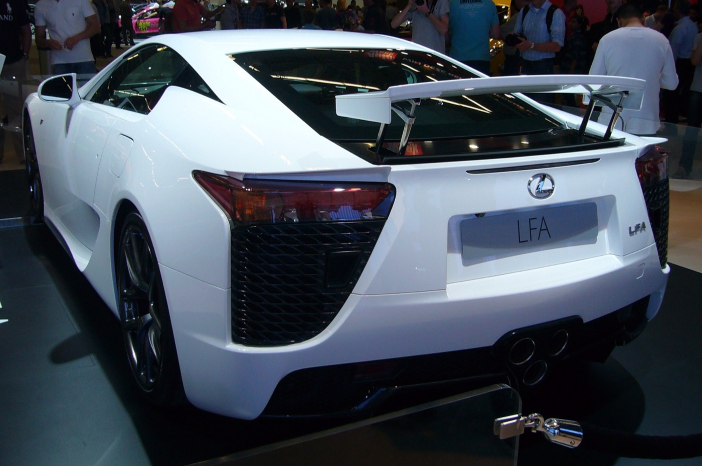 Rear three-quarter view of a white Lexus LFA with its rear wing raised and triple exhaust outlets