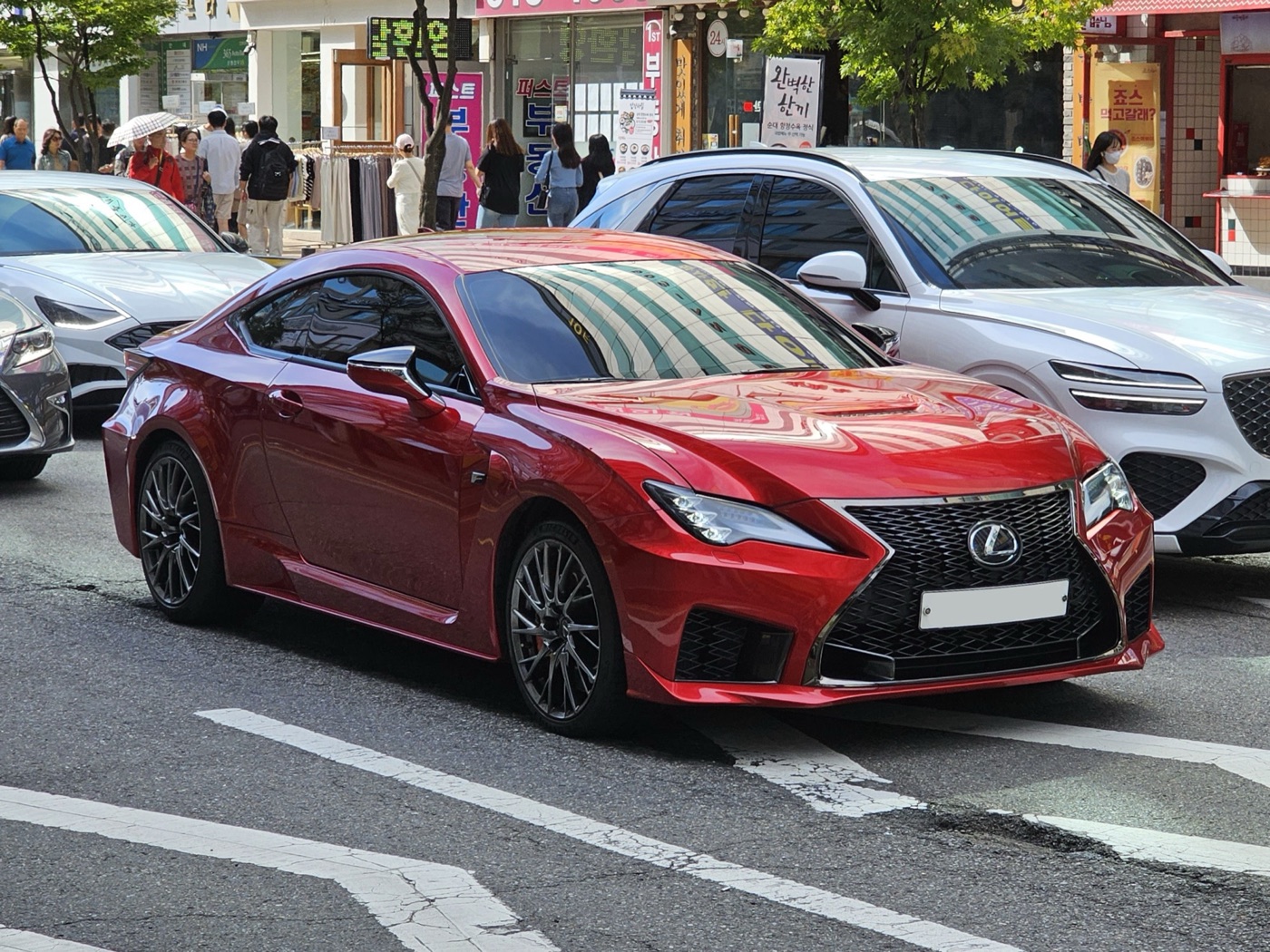 Red facelifted Lexus RC F coupe in a city street, with stacked LED headlamps and a spindle grille with a lower lip opening