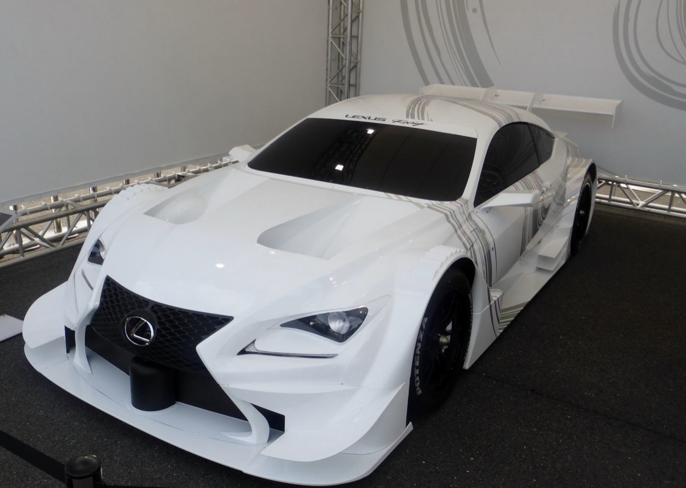 White Lexus RC F GT500 racing car with a wide body, bonnet vents and a large rear wing on display