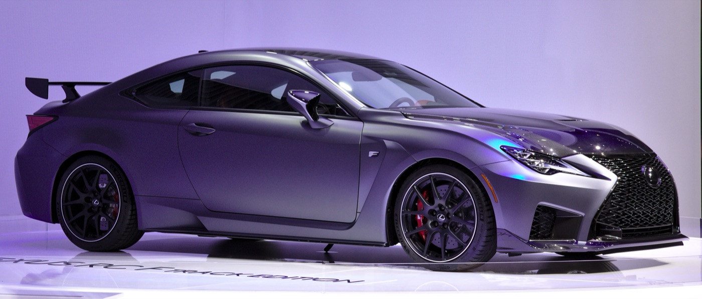 Matt grey Lexus RC F Track Edition with a fixed carbon rear wing and black wheels on a motor show stand