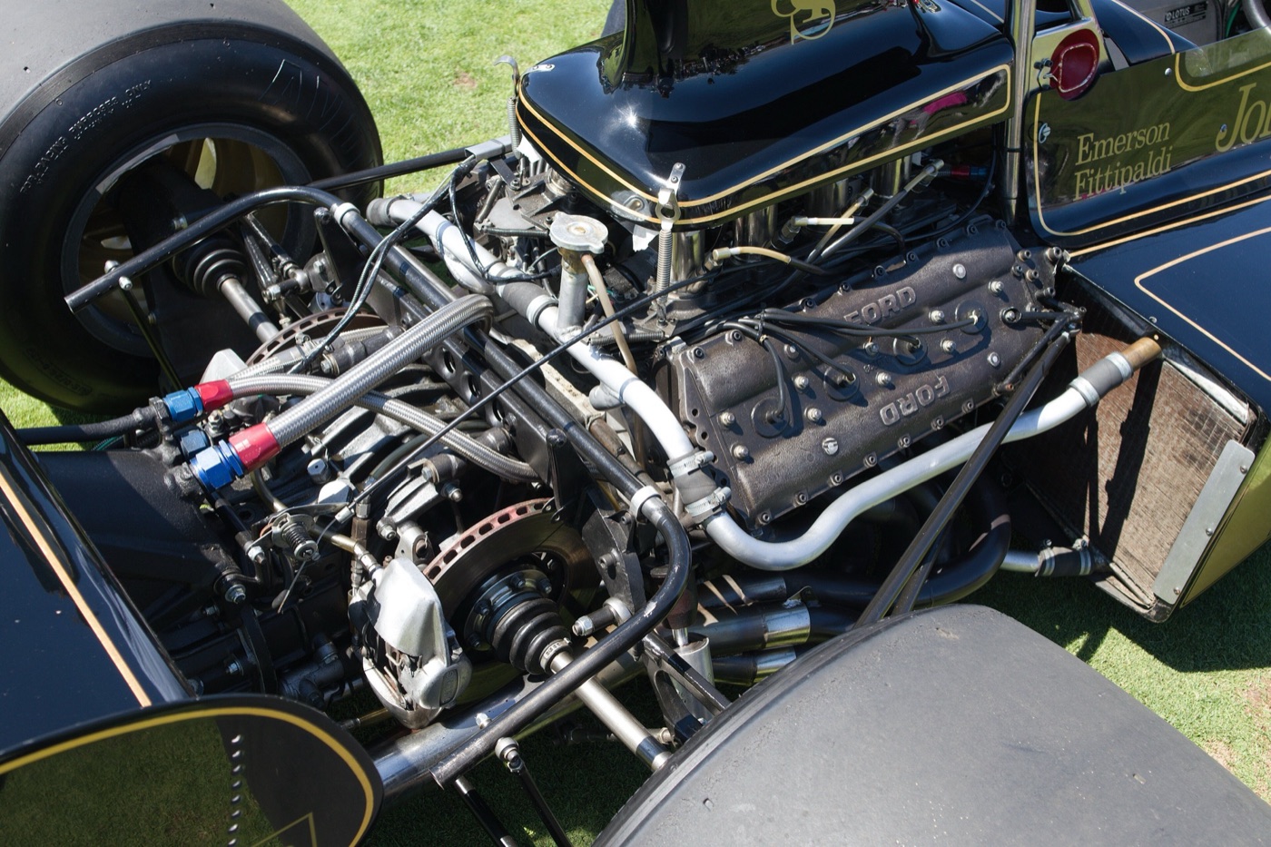 Rear of a black and gold Lotus 72E with the bodywork off, showing the Ford Cosworth DFV V8, the gearbox and an inboard rear brake disc