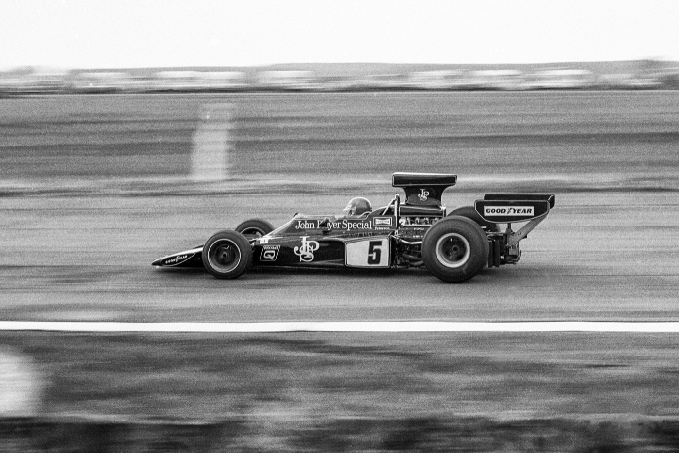 Black and white panning photograph of Ronnie Peterson in a John Player Special Lotus 72E numbered 5 at speed
