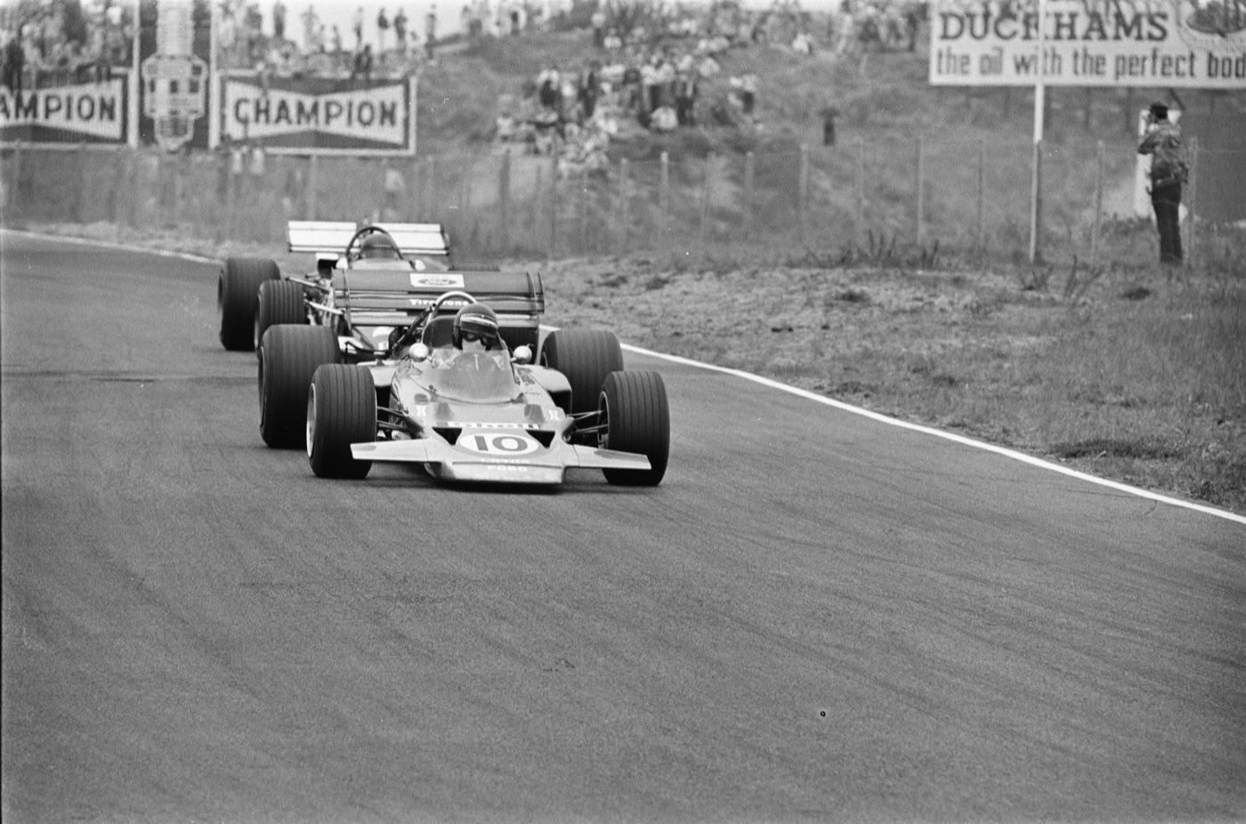 Black and white photograph of Jochen Rindt in the Lotus 72 numbered 10 leading Jacky Ickx