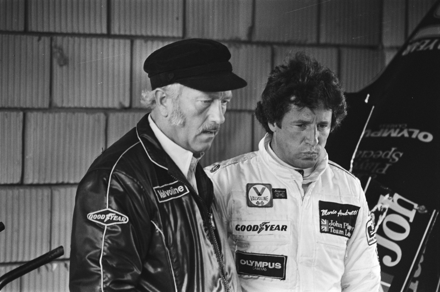 Colin Chapman in a black cap and Goodyear jacket beside Mario Andretti in white John Player Team Lotus overalls, Zandvoort 1978