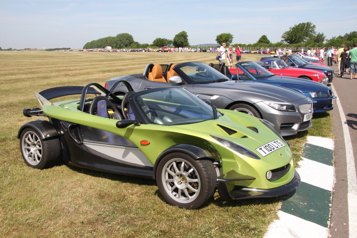 Green and silver Lotus 340R with exposed wheels and roll hoops parked at the front of a row of roadsters at Goodwood