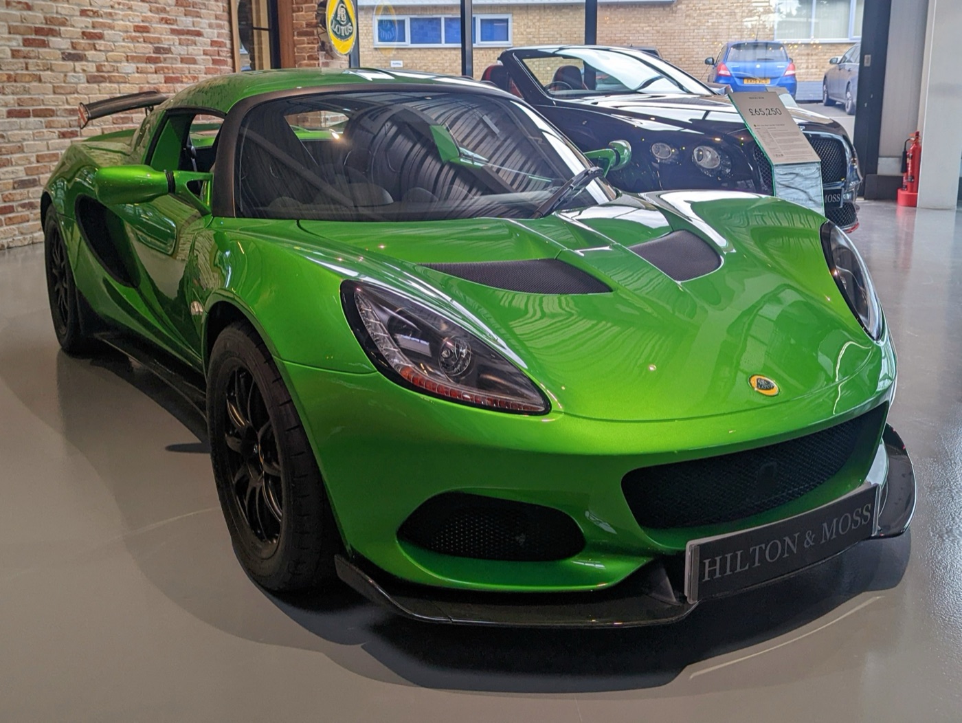 Bright green Lotus Elise Cup 250 Final Edition with black wheels and a front splitter in a car showroom