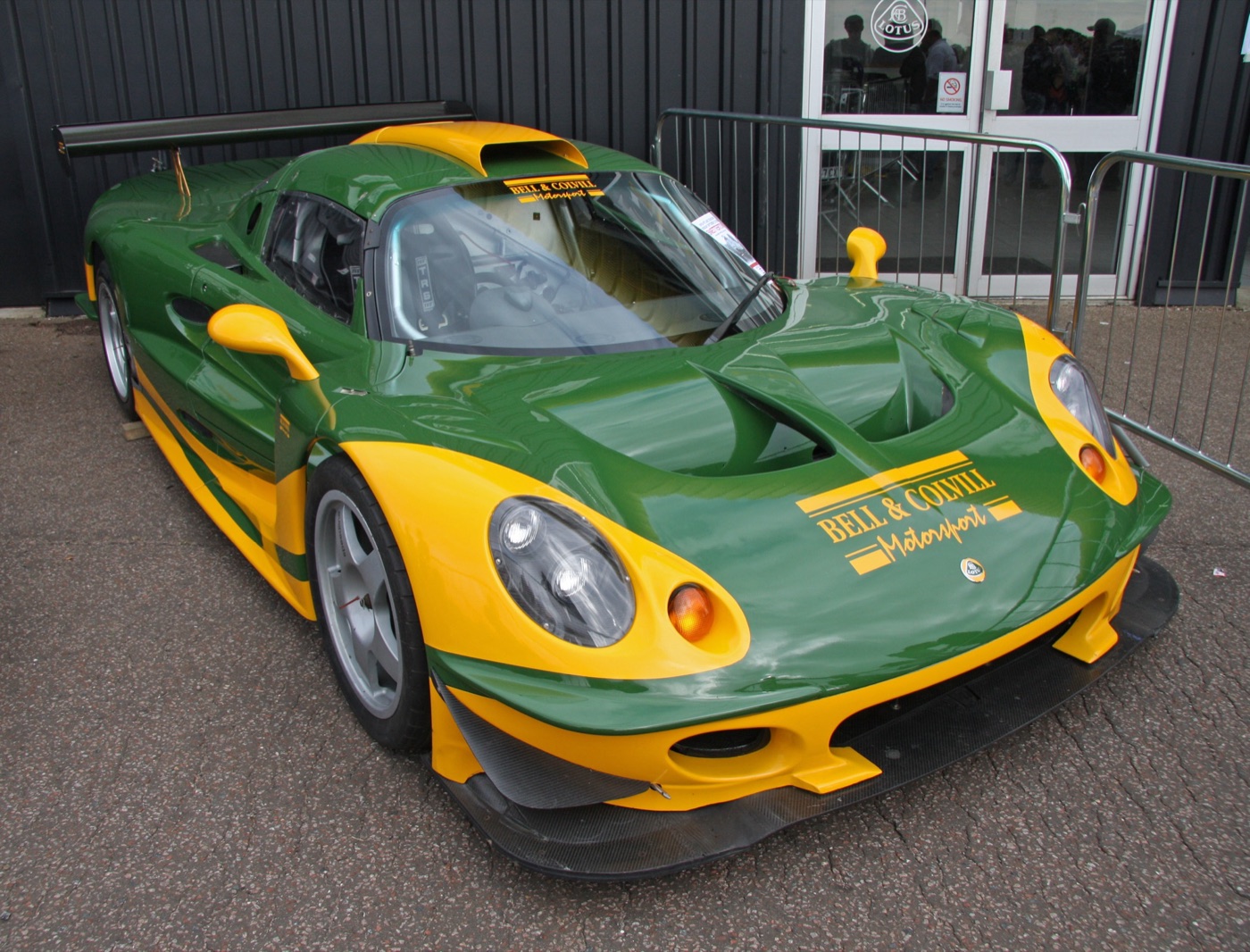 Green and yellow Lotus Elise GT1 race car with a large rear wing and Bell and Colvill Motorsport lettering on the bonnet
