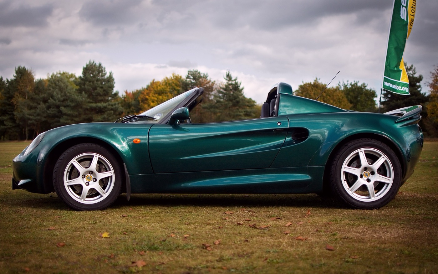 Dark green Lotus Elise Series 1 111S in profile on grass, with six-spoke wheels and a raised rear spoiler
