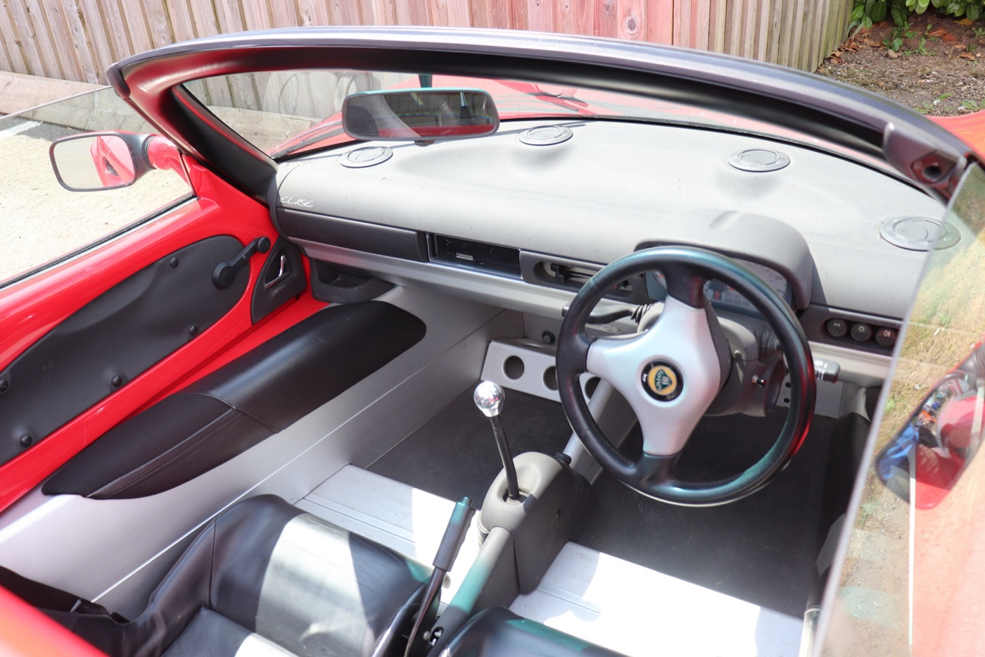Interior of a 1997 Lotus Elise with bare aluminium floor and sills, a small three-spoke steering wheel and silver and black seats