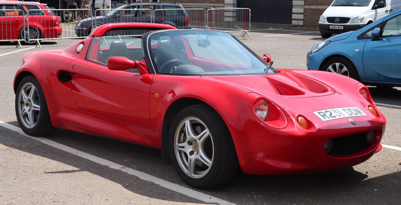 Red 1997 Lotus Elise Series 1 roadster with its roof off, seen from the front three-quarter in a car park
