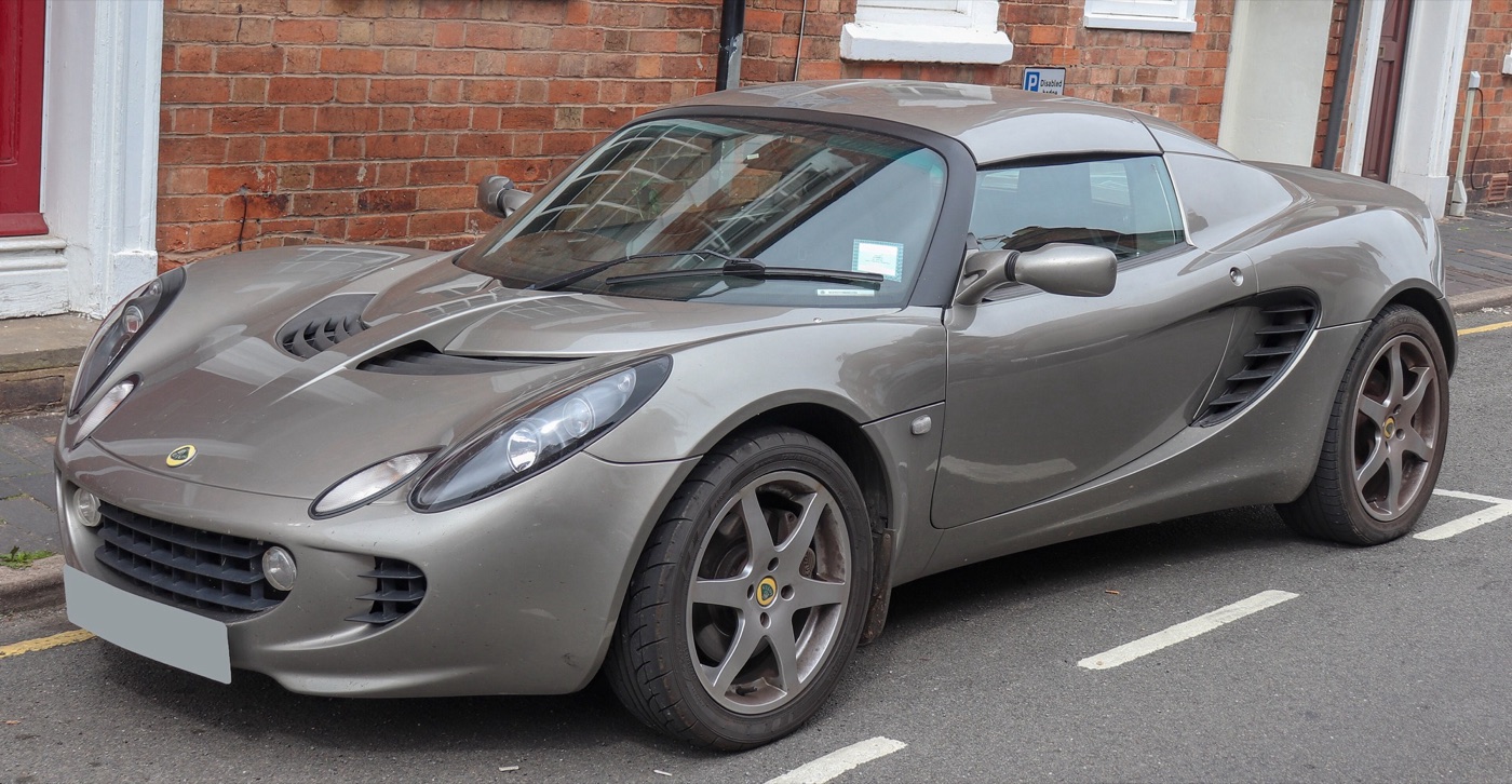 Grey 2008 Lotus Elise S Touring Series 2 with a hard top, parked by a brick house