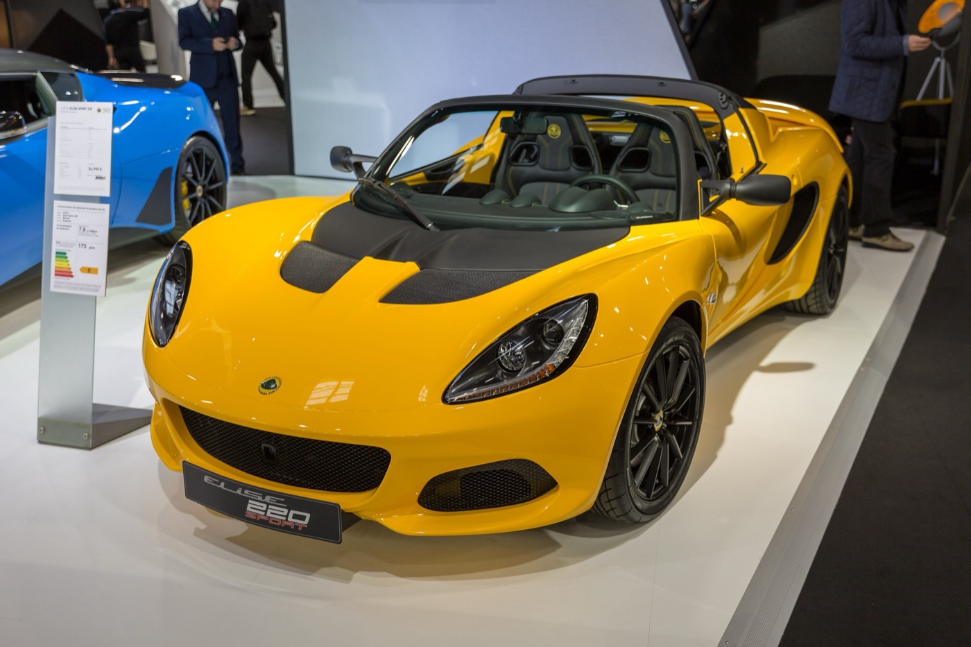 Yellow Lotus Elise Sport 220 roadster with a black bonnet panel and black wheels on a motor show stand