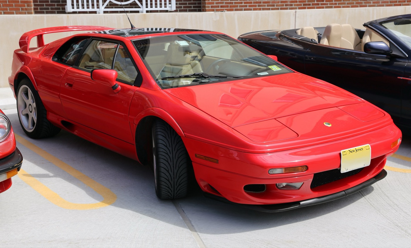 Red 1999 Lotus Esprit V8 with a high rear wing and five-spoke wheels in a car park