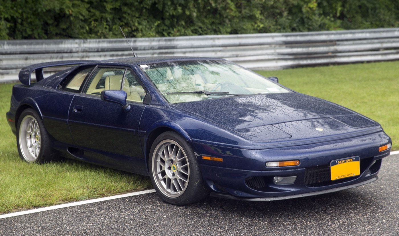 Dark blue 2003 Lotus Esprit V8 with a tall rear wing and silver multi-spoke wheels, seen from the front three-quarter