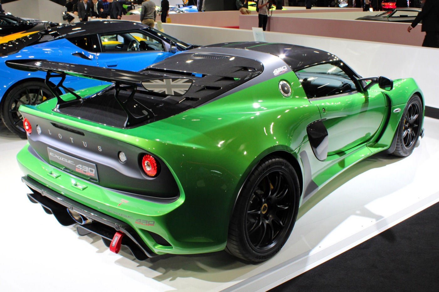 Green Lotus Exige Cup 430 with carbon roof and large rear wing, seen from the rear three-quarter on a motor show stand