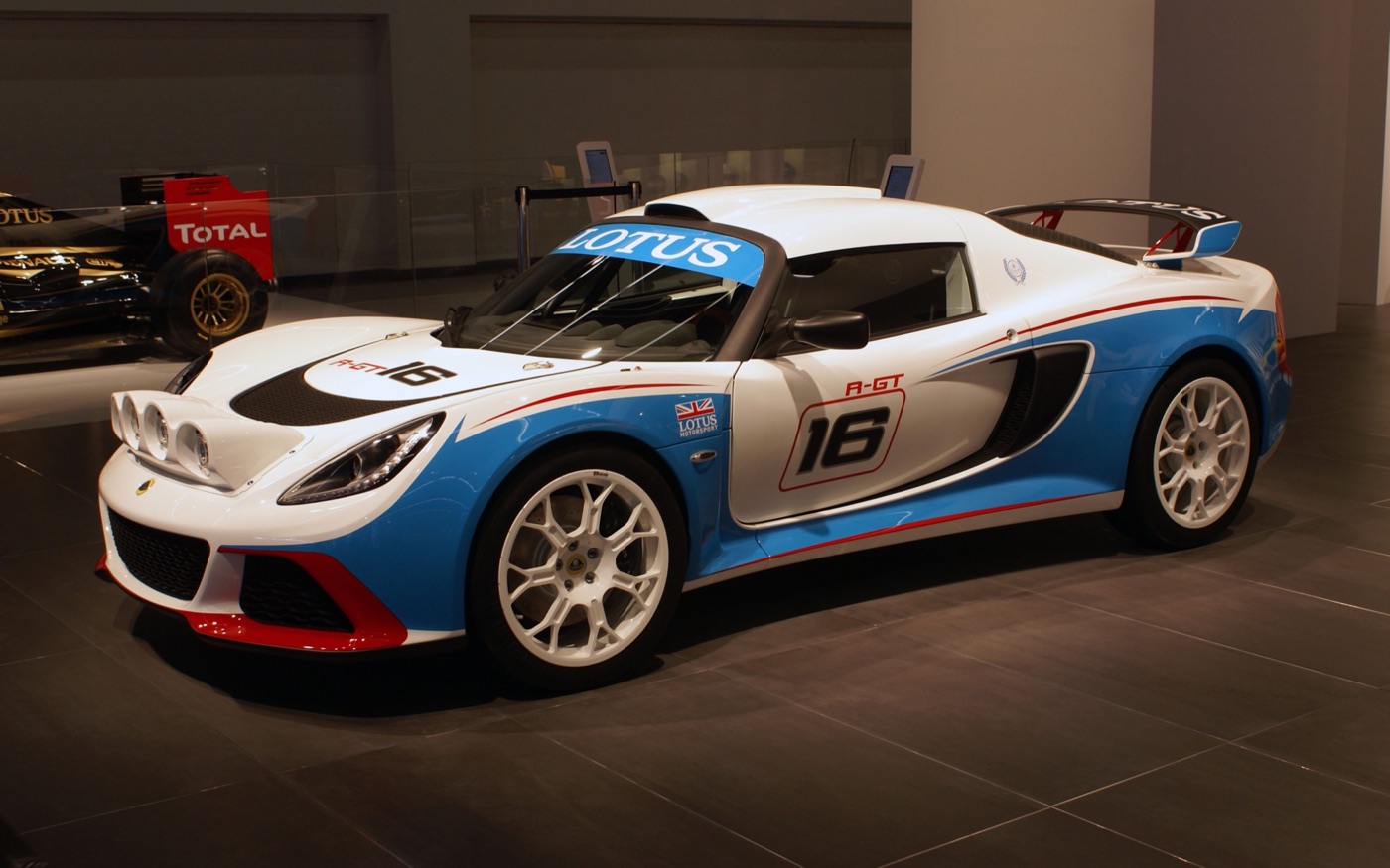 Lotus Exige R-GT rally car in white, blue and red livery with number 16 on a motor show stand