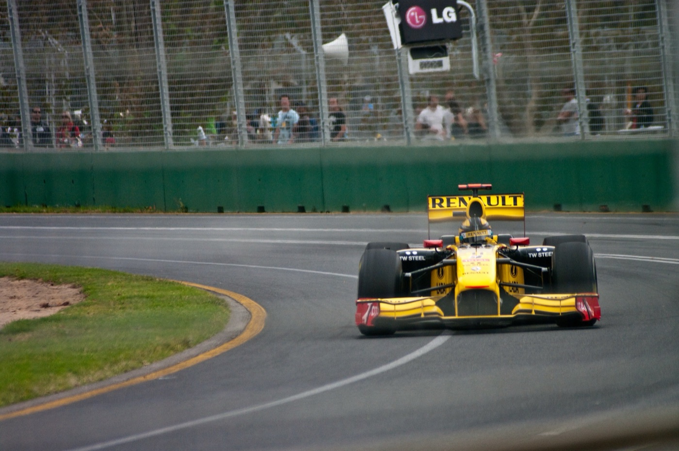 Yellow and black Renault R30 Formula One car on track in front of a catch fence and spectators