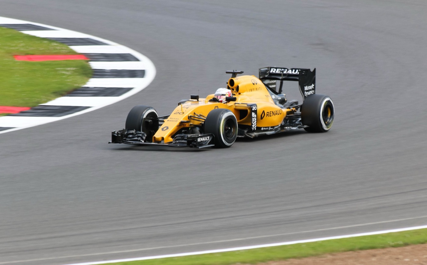 Yellow and black Renault RS16 Formula One car cornering past a chequered kerb