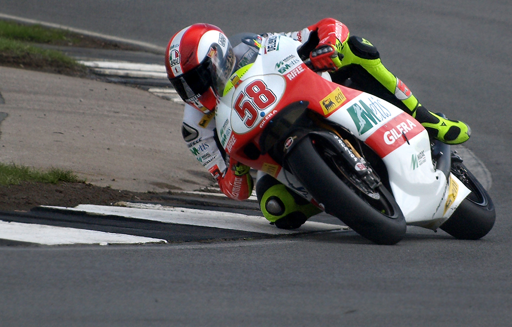 Marco Simoncelli leaning the white and red number 58 Gilera into a corner at Donington Park