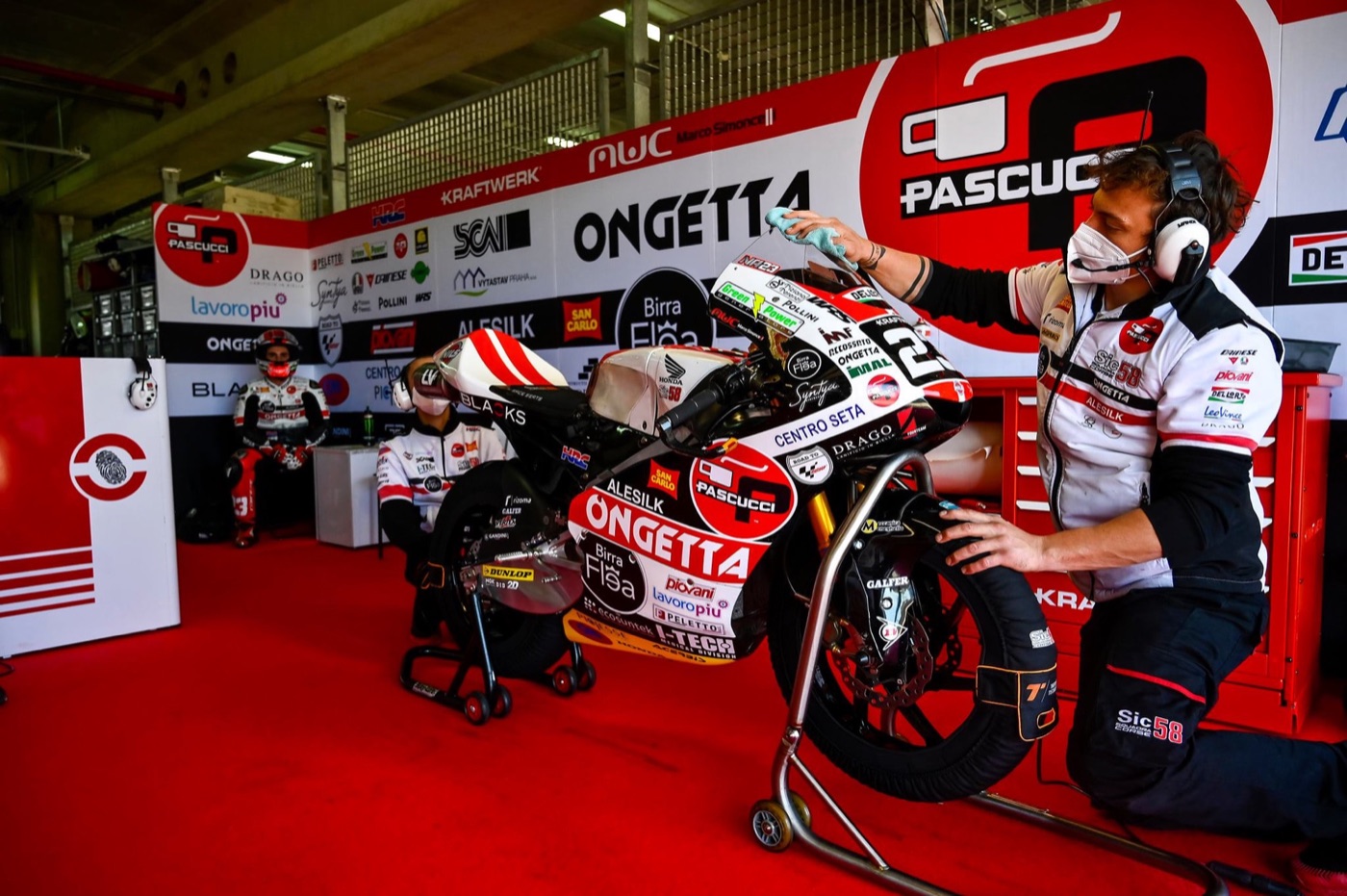 A mechanic working on a SIC58 Squadra Corse Moto3 bike in the team garage