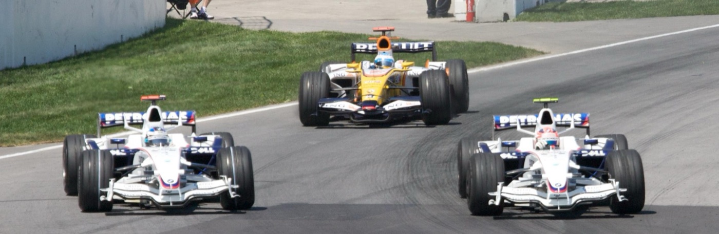 Two white and blue BMW Sauber F1.08 cars side by side on the track at Montreal, with a yellow Renault close behind