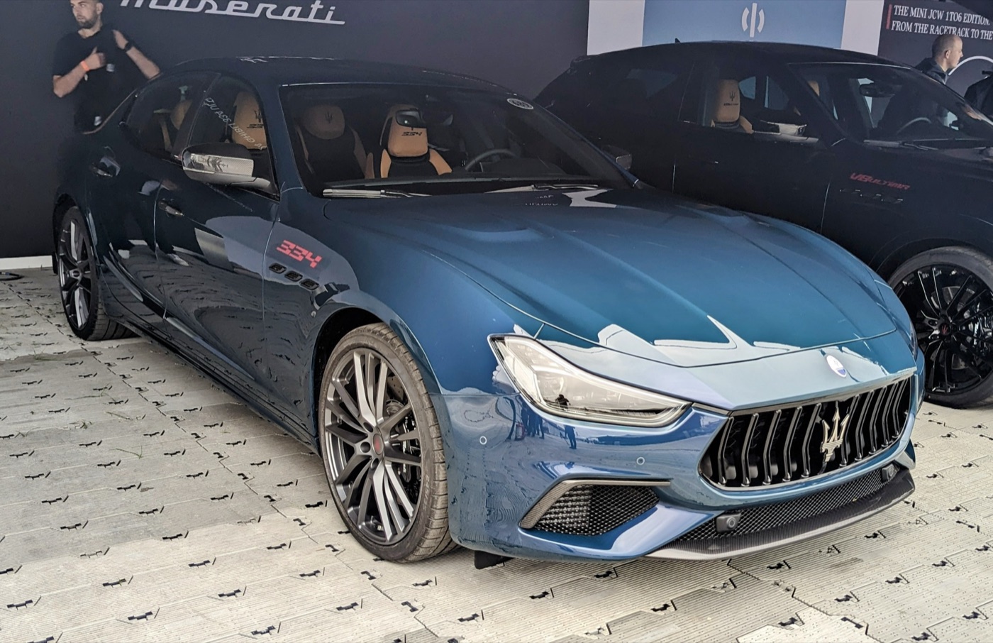 Blue Maserati Ghibli 334 Ultima on a show stand, front three-quarter view, with a red 334 badge on the front wing