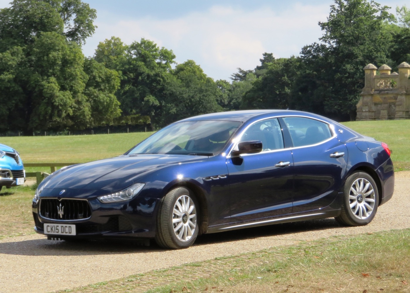 Dark blue 2015 Maserati Ghibli diesel saloon parked on grass in front of trees, seen from the front three-quarter