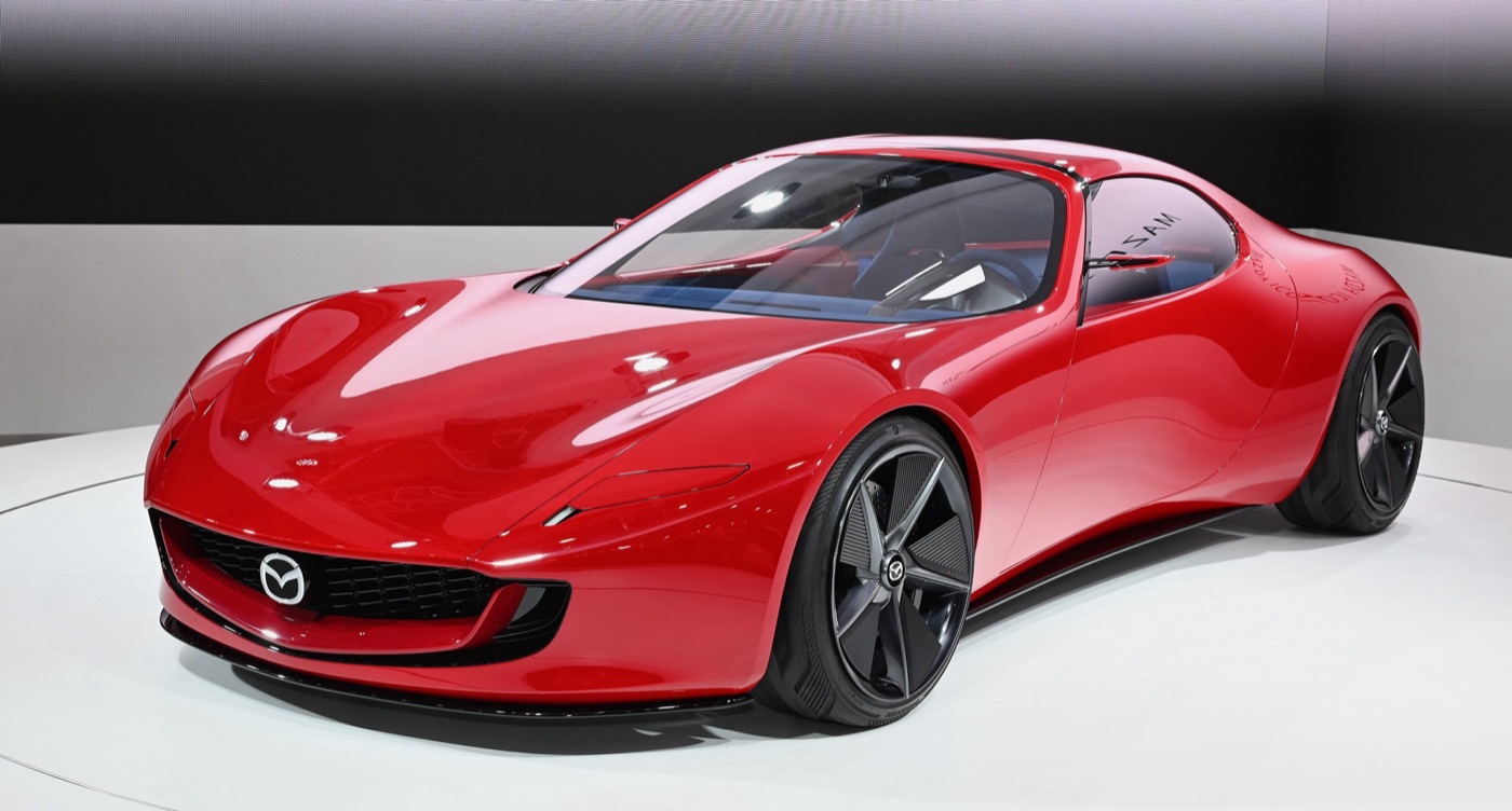 Red Mazda Iconic SP concept coupé with a long low bonnet and black wheels on a white show stand