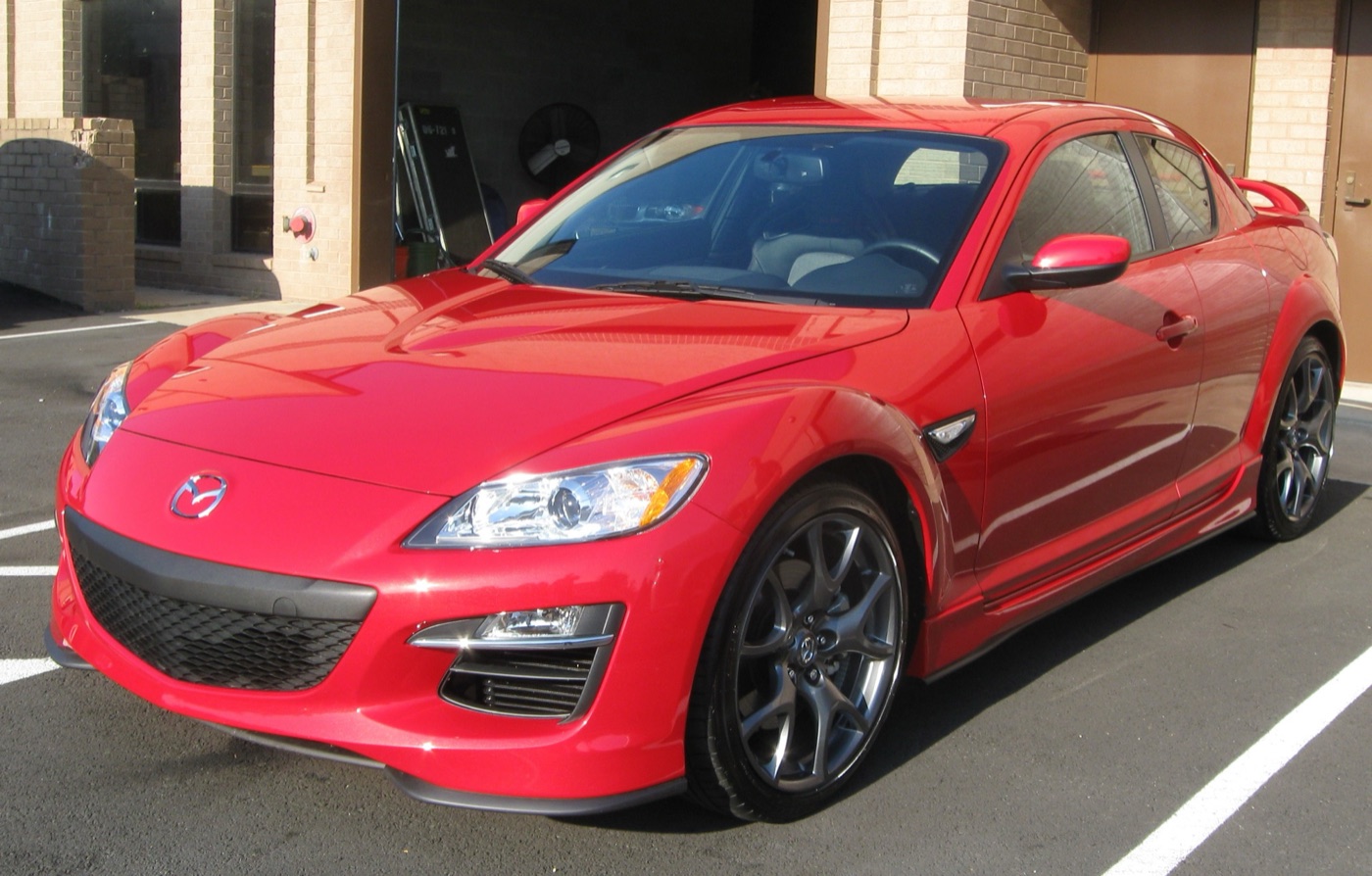 Red facelifted Mazda RX-8 R3 with a lower front splitter, side skirts and dark 19-inch wheels in a car park