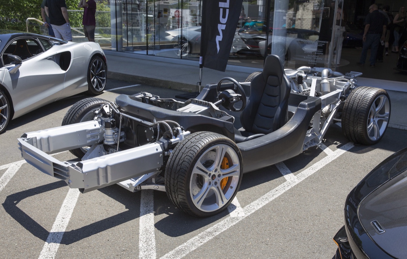 McLaren 12C display chassis showing the black carbon MonoCell tub, aluminium front frame, seat, wheels and engine