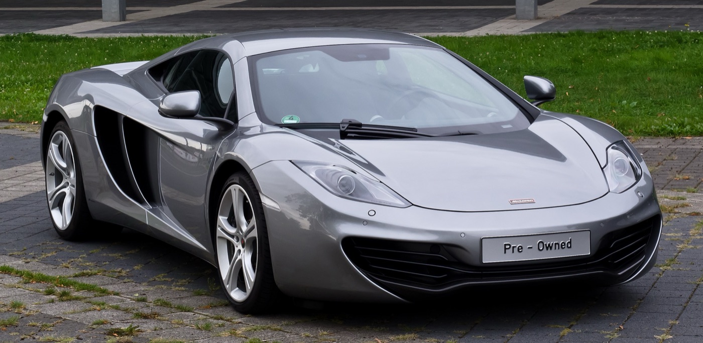 Silver McLaren MP4-12C coupé with a Pre-Owned plate parked on a forecourt