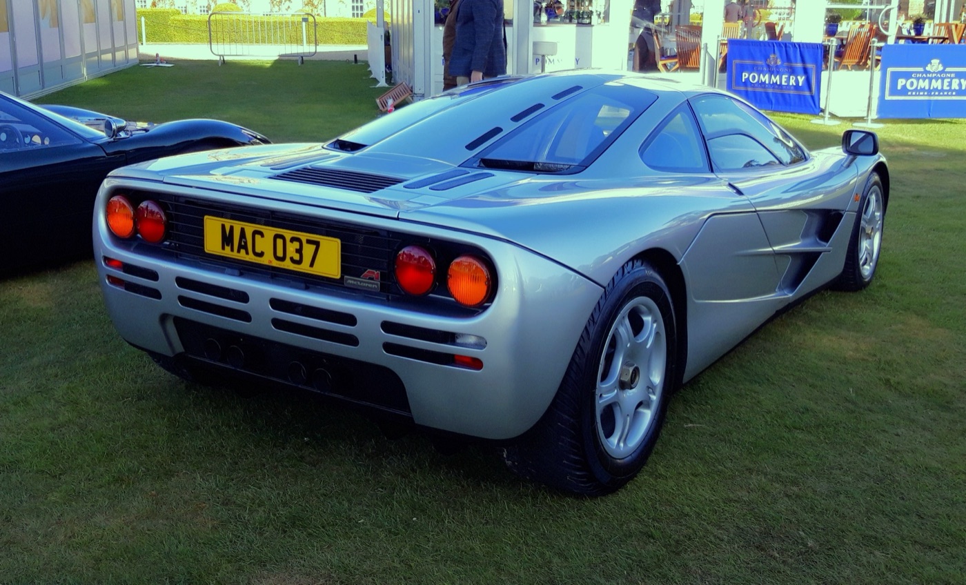 Silver McLaren F1 from the rear three-quarter, showing its round tail lights and louvred engine cover