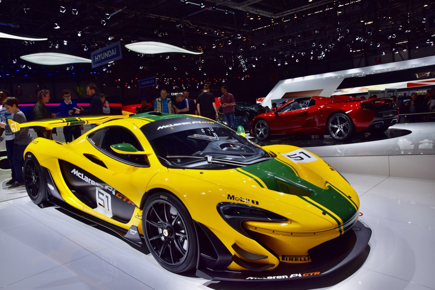 Yellow and green McLaren P1 GTR with a large fixed rear wing on a motor show stand