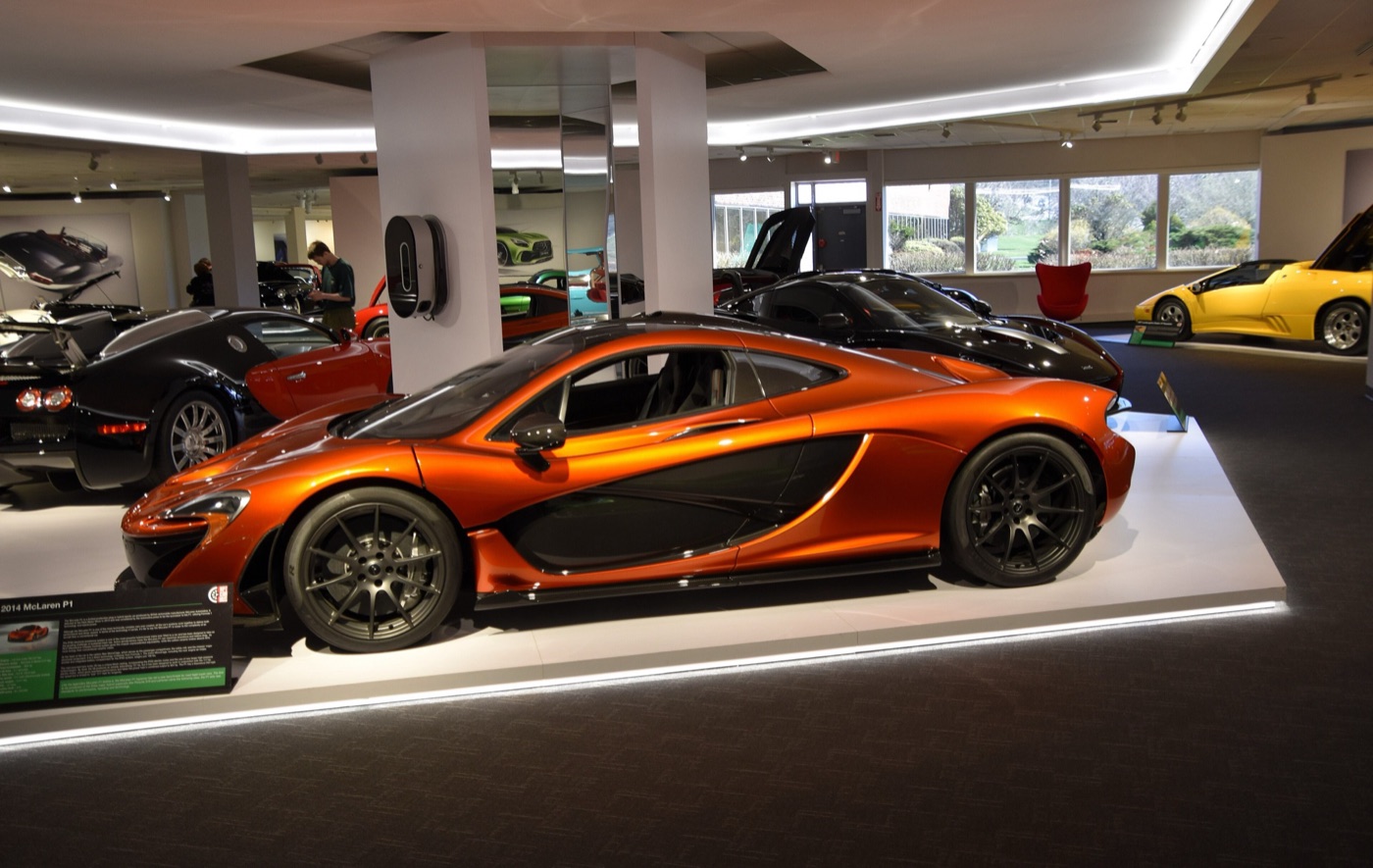 Orange McLaren P1 in side profile on display in a car museum