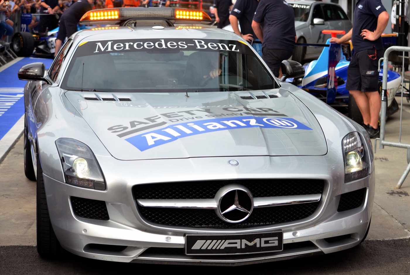 Silver SLS AMG Formula One safety car with Safety Car and Allianz lettering on the bonnet and a roof light bar, in a pit lane