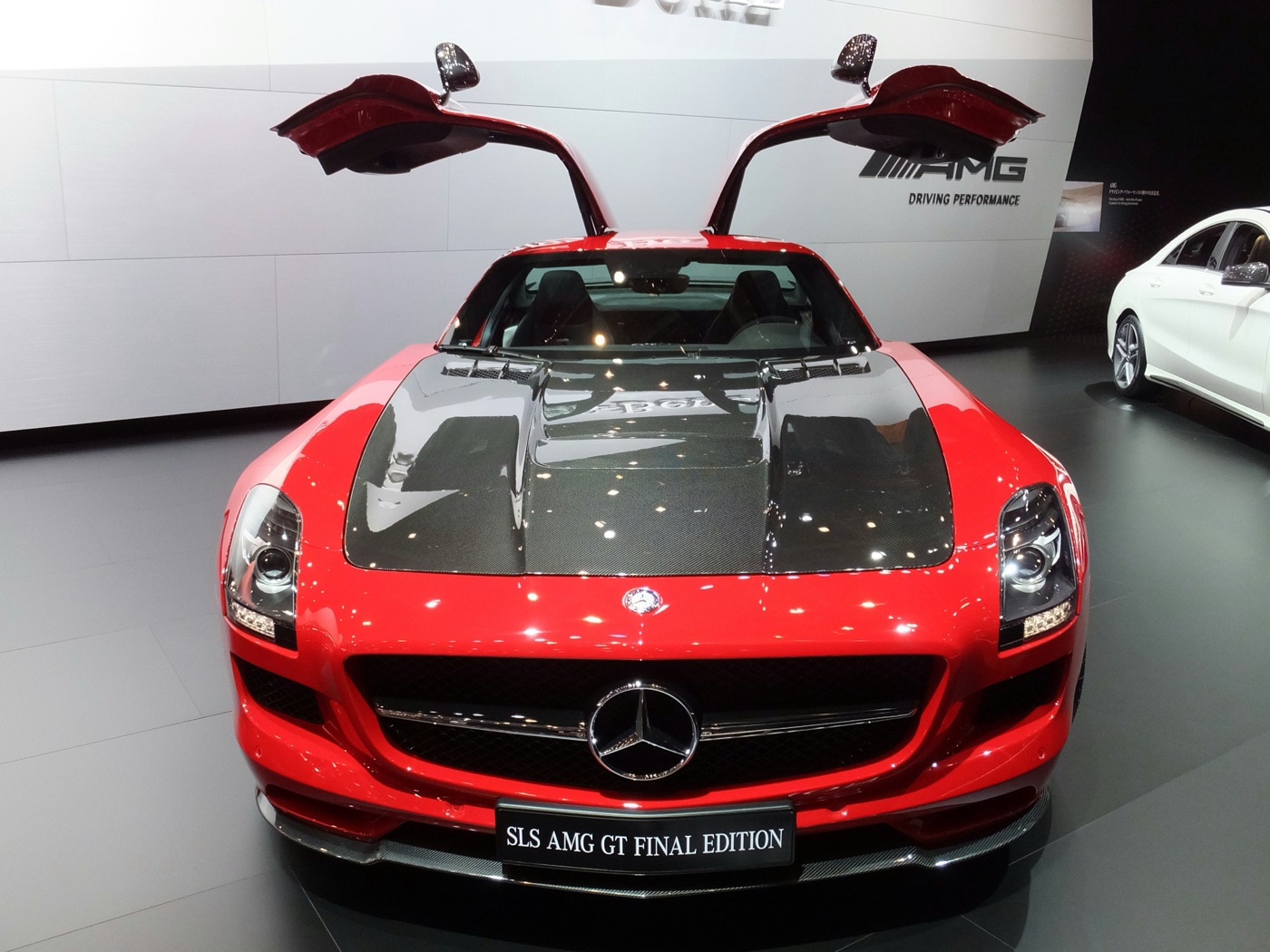 Red SLS AMG GT Final Edition with a bare carbon-fibre bonnet and gullwing doors open at the Tokyo motor show