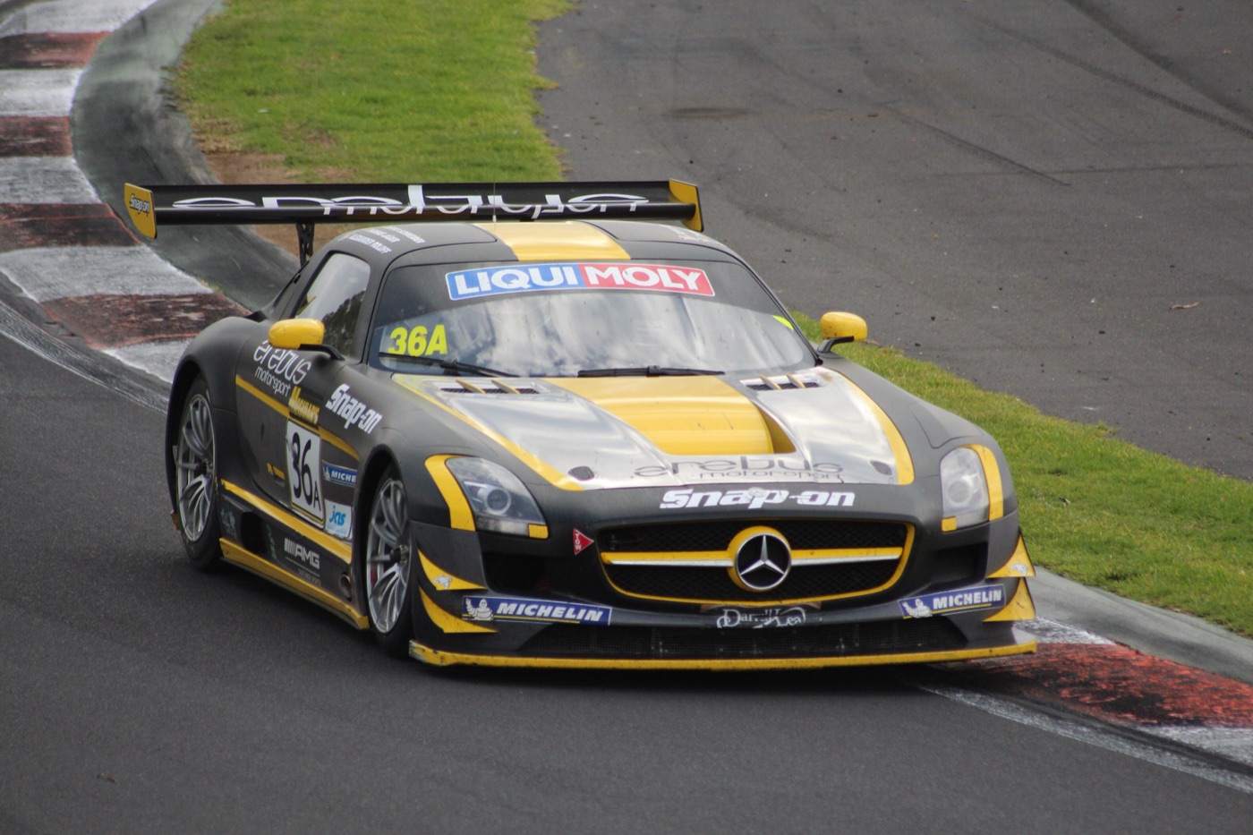Black and yellow Erebus Mercedes SLS AMG GT3 with Liqui Moly and Snap-on decals cornering on the descent at Mount Panorama