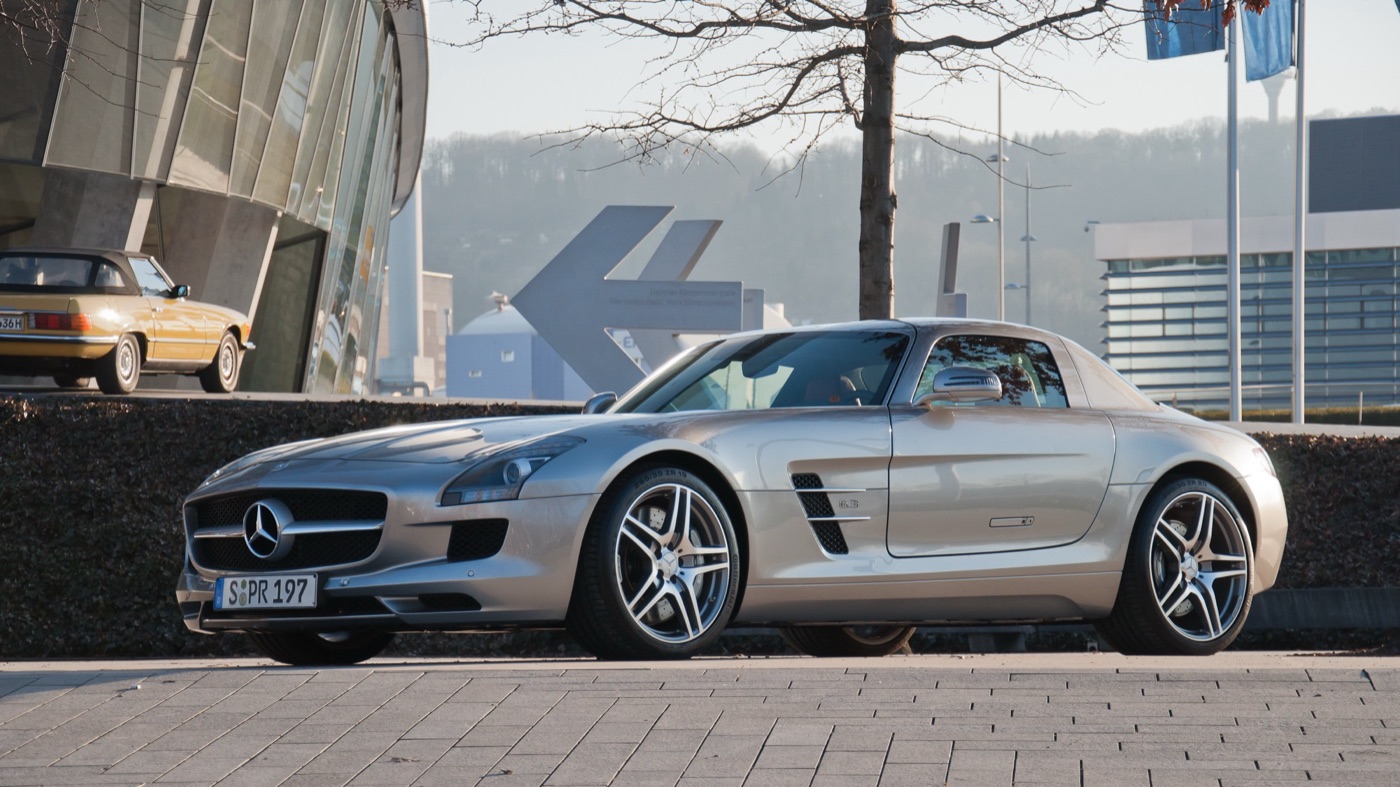 Silver Mercedes SLS AMG coupé seen from the front three-quarters, parked outside the Mercedes-Benz Museum in Stuttgart