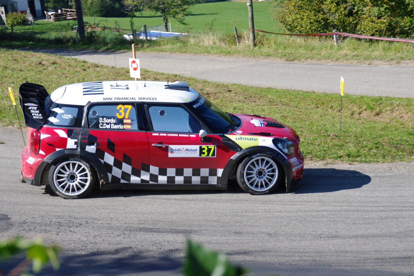 Red and white MINI John Cooper Works WRC number 37 with chequered livery on a tarmac stage