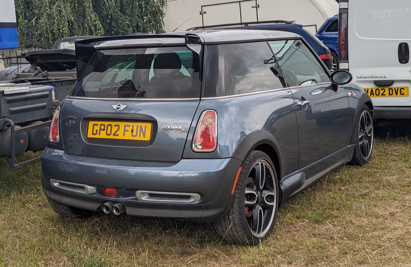 Rear three-quarter view of a grey-blue MINI Cooper S John Cooper Works GP with its wing-shaped roof spoiler, central twin exhaust and red brake callipers