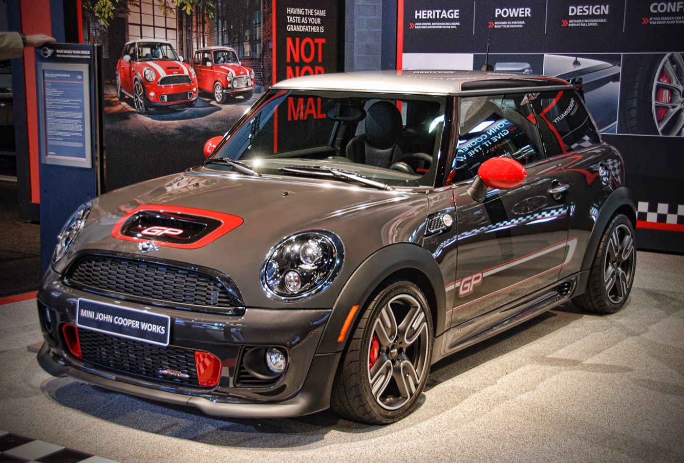 Dark grey 2013 MINI John Cooper Works GP with red bonnet scoop surround, red mirror caps and GP side stripes on a motor show stand