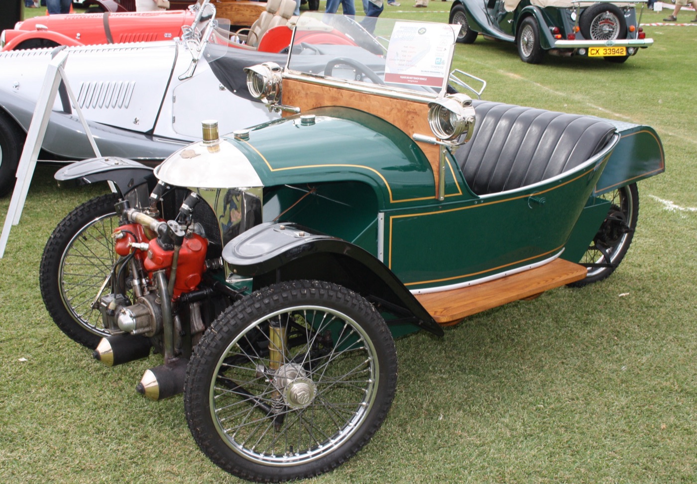 Green 1918 Morgan Grand Prix three-wheeler with a polished radiator, red V-twin engine, wire wheels and black leather seat