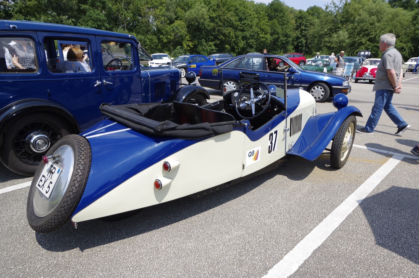 Cream and blue 1934 Morgan F4 three-wheeler with a folded black hood and a spare wheel on its tail, in a car park